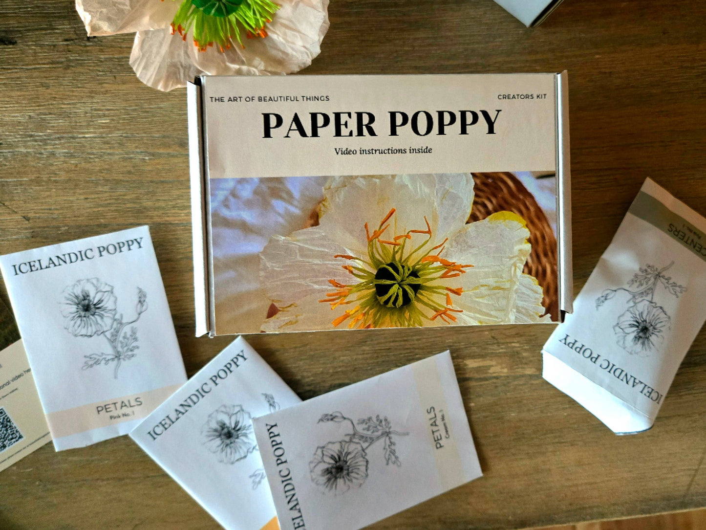 Box of Paper Poppy products on a wooden surface with flower packaging.